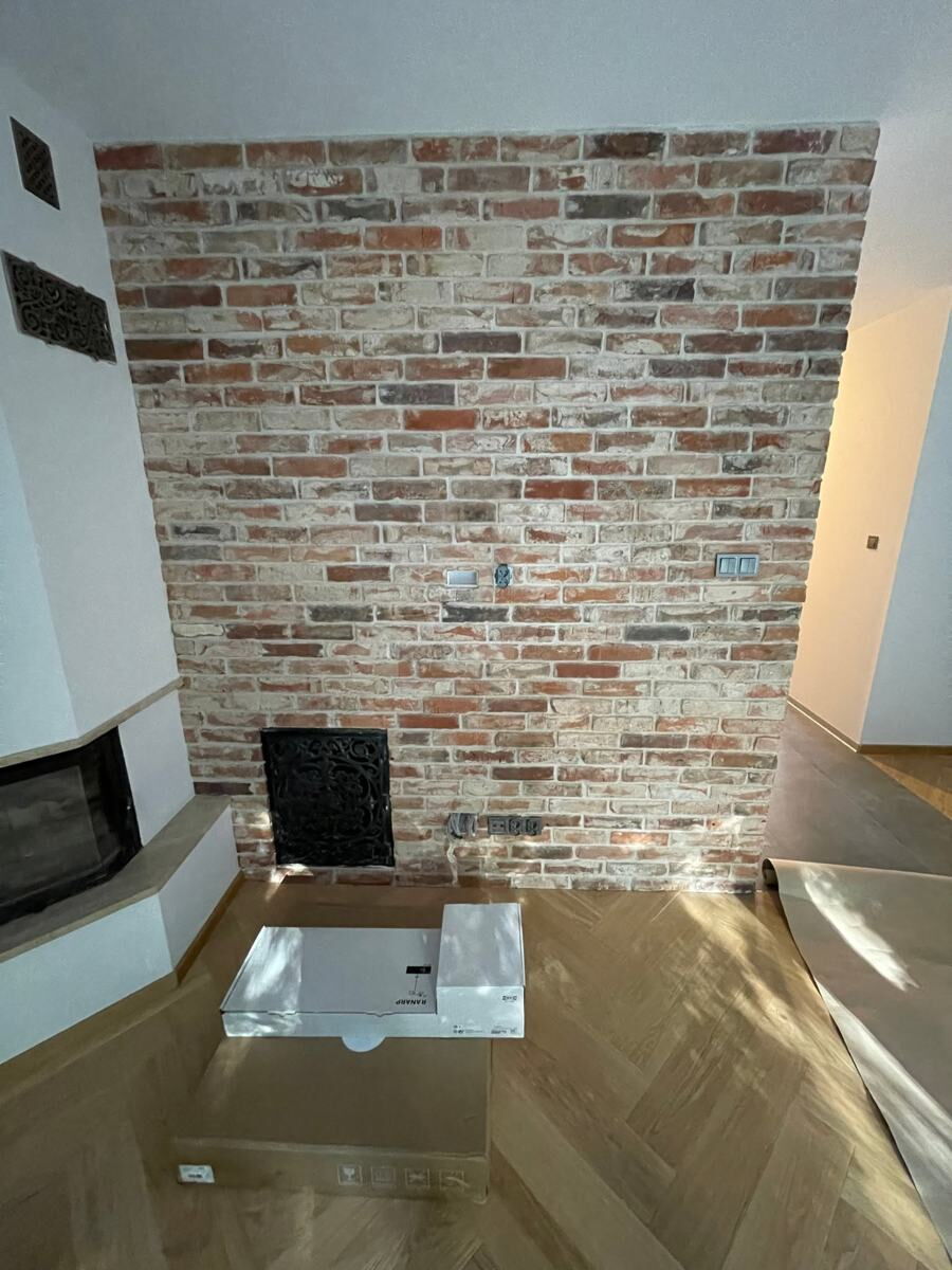 Salon ze ścianą z cegły i kominkiem